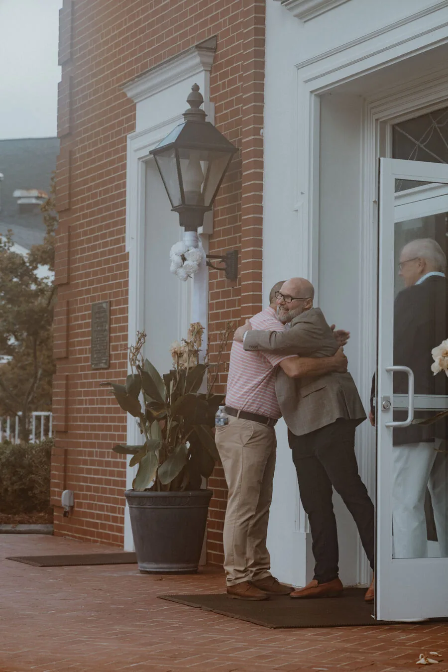 Two men hugging at the front doors.