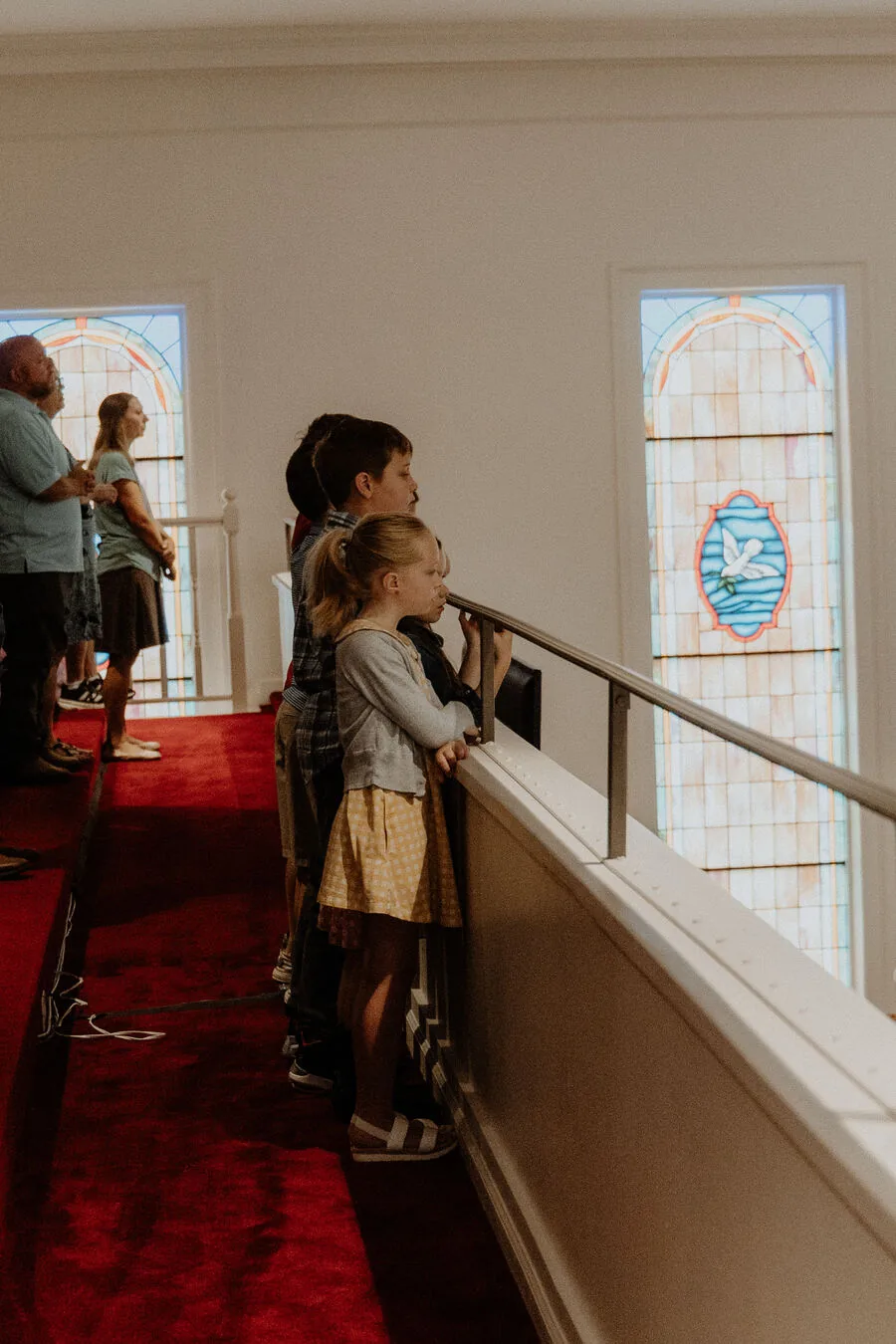 Standing at the balcony rail beside the stained glass windows.
