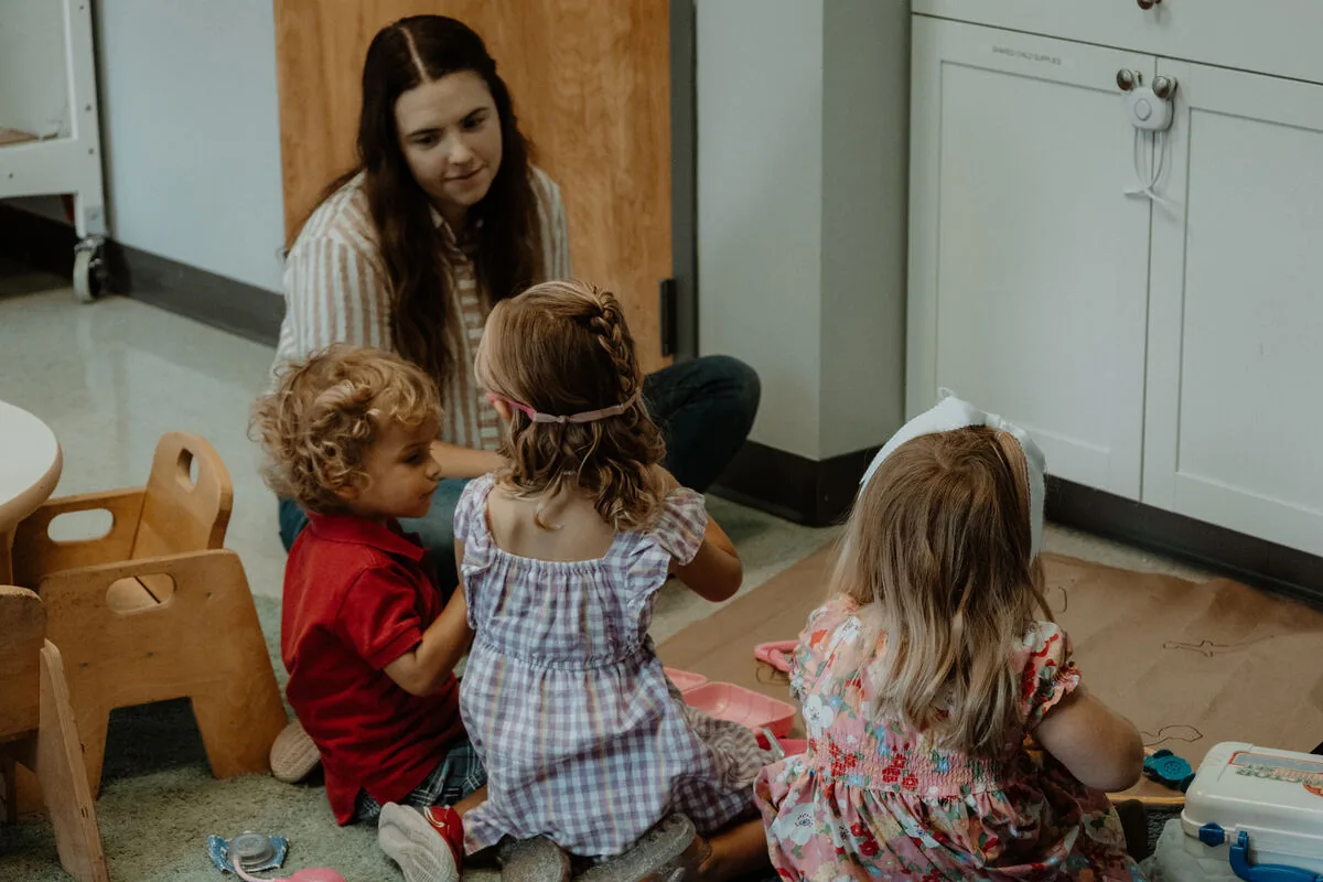 Young children playing in the kids room with a leader.
