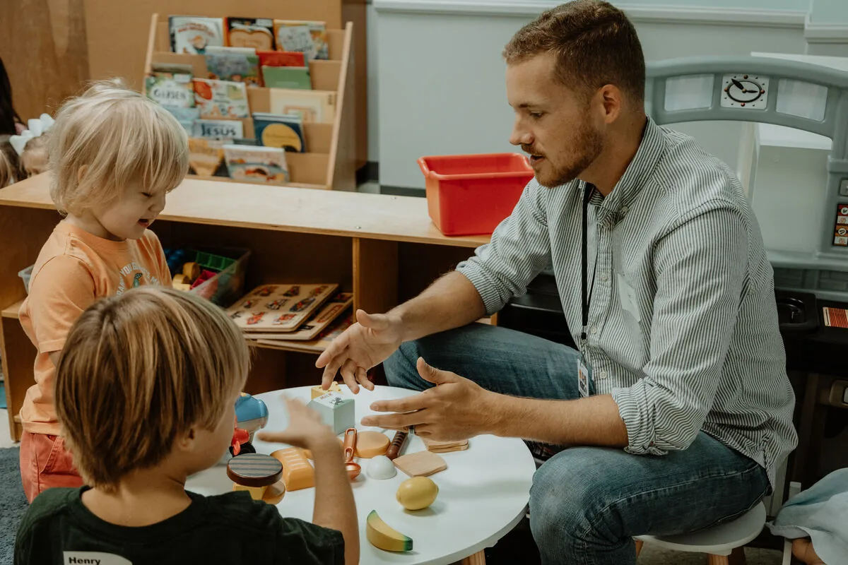 A leader at the table with children in the kids room.