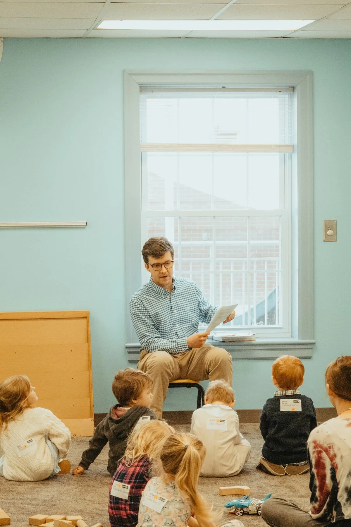 A leader reading to children sitting on the floor.
