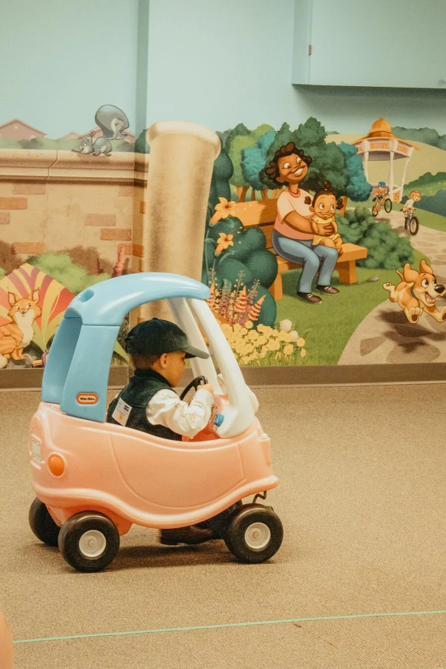 A child in a toy car in the hallway.