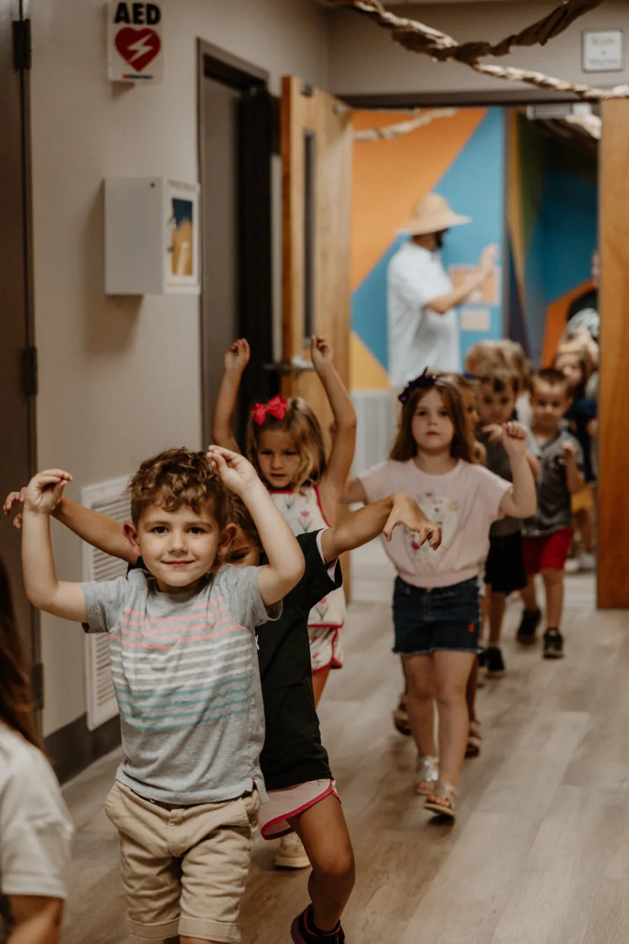 Children running down the hallway with their hands up.