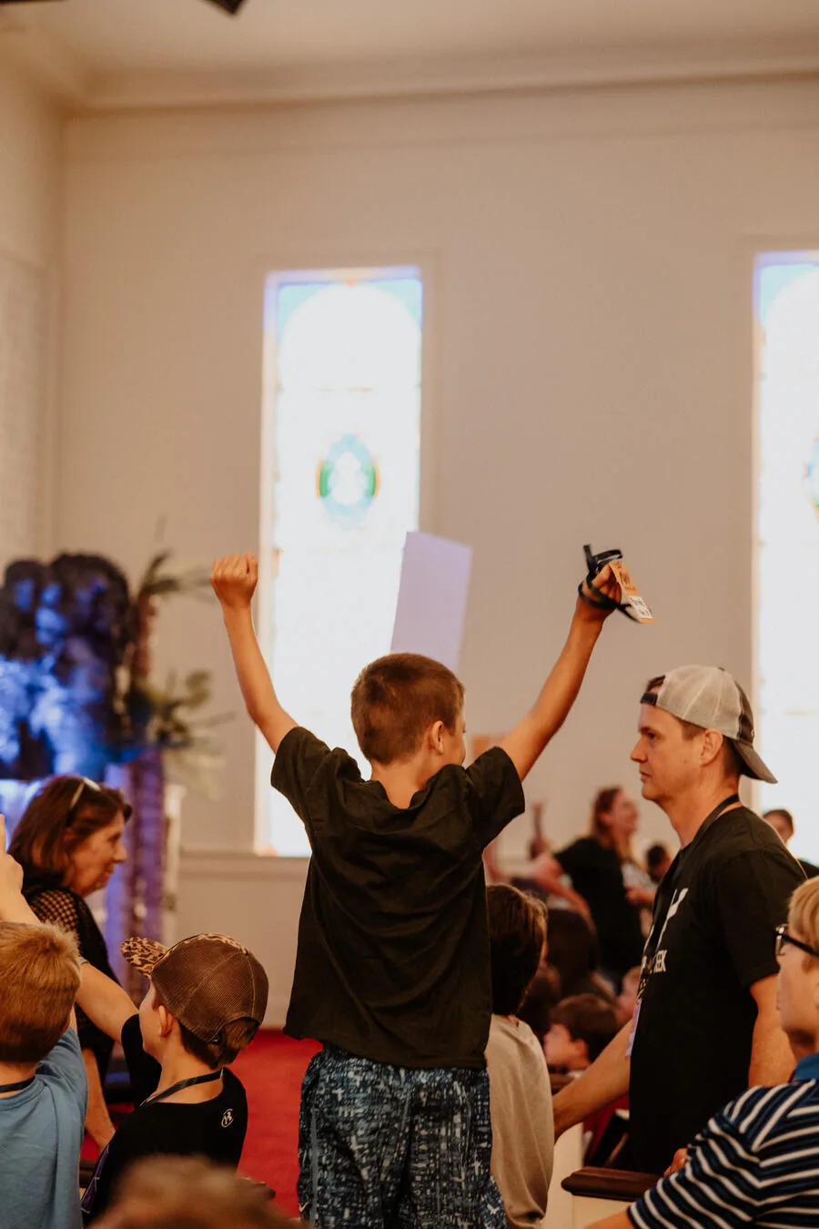 A child with both hands up during a song.