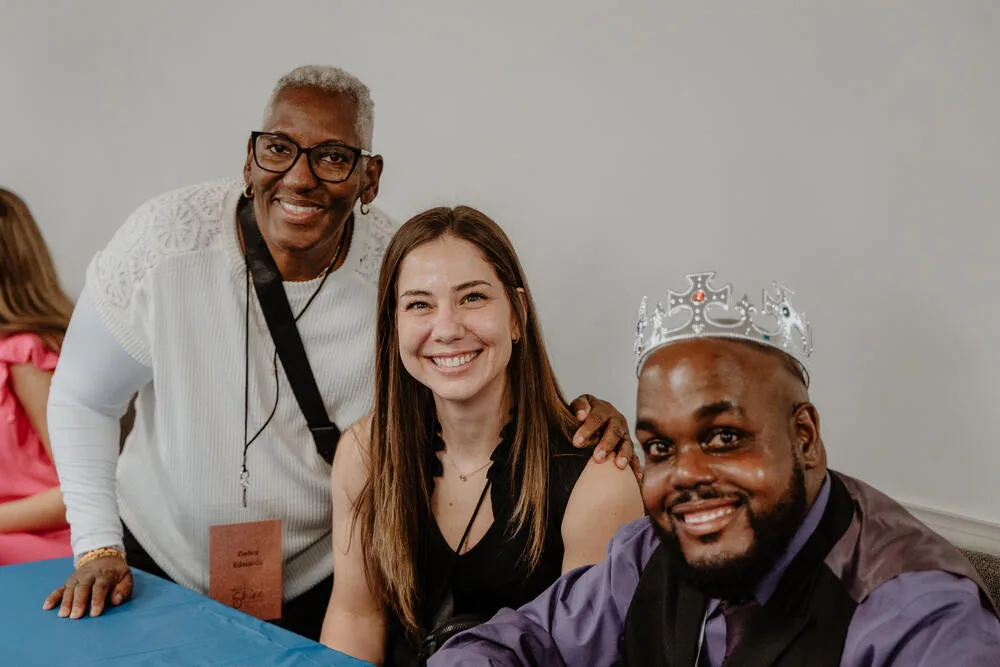 Three friends, one of them wearing a crown.
