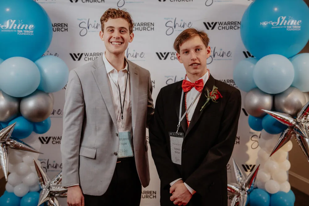 Two guests in tuxedos at the backdrop.