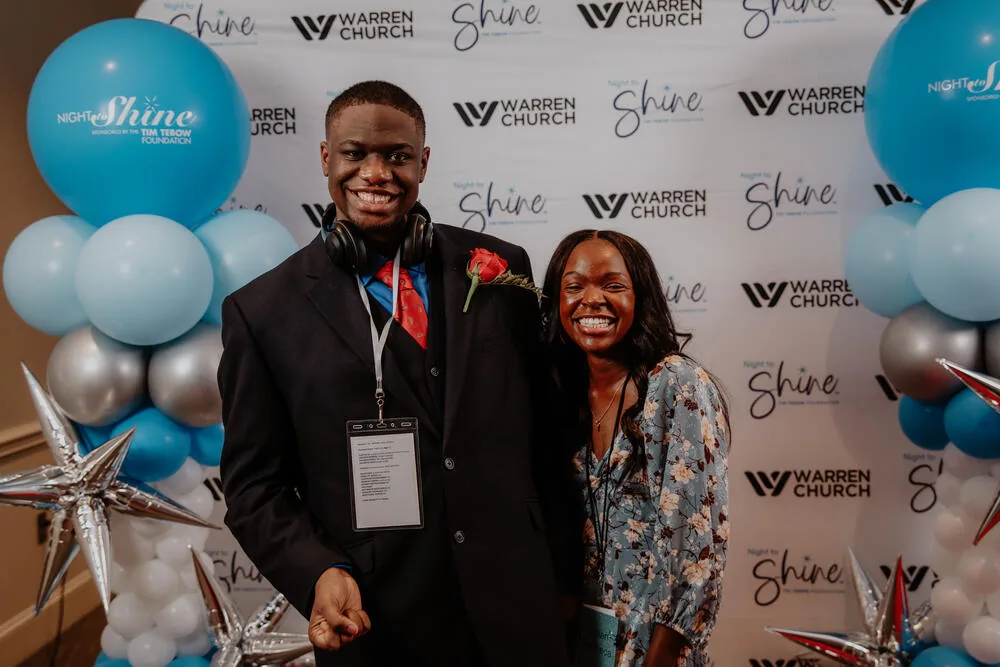 A guest and a volunteer at the backdrop.
