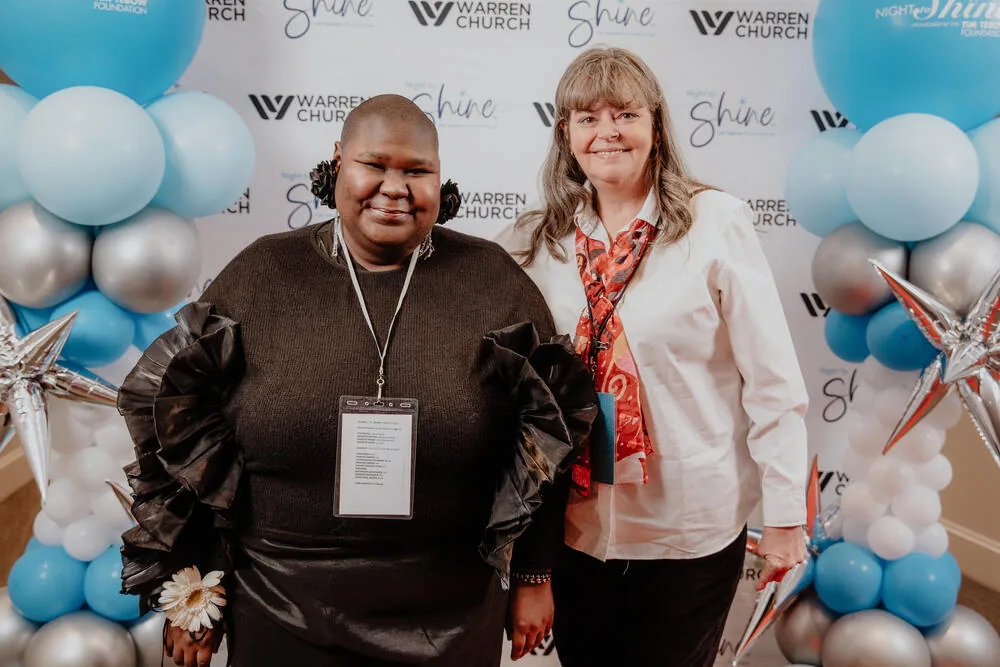 A guest and a volunteer at the backdrop.