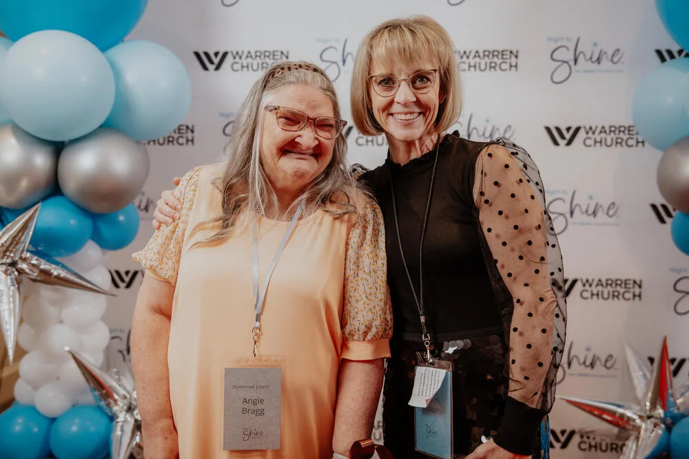 A guest and a volunteer at the backdrop.