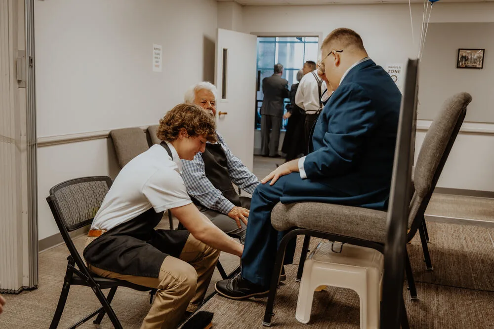 A volunteer shining a guest's shoes.