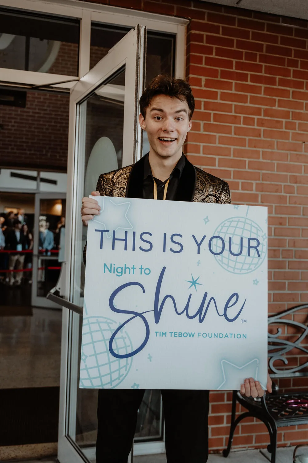 A guest holding a This Is Your Night to Shine sign.