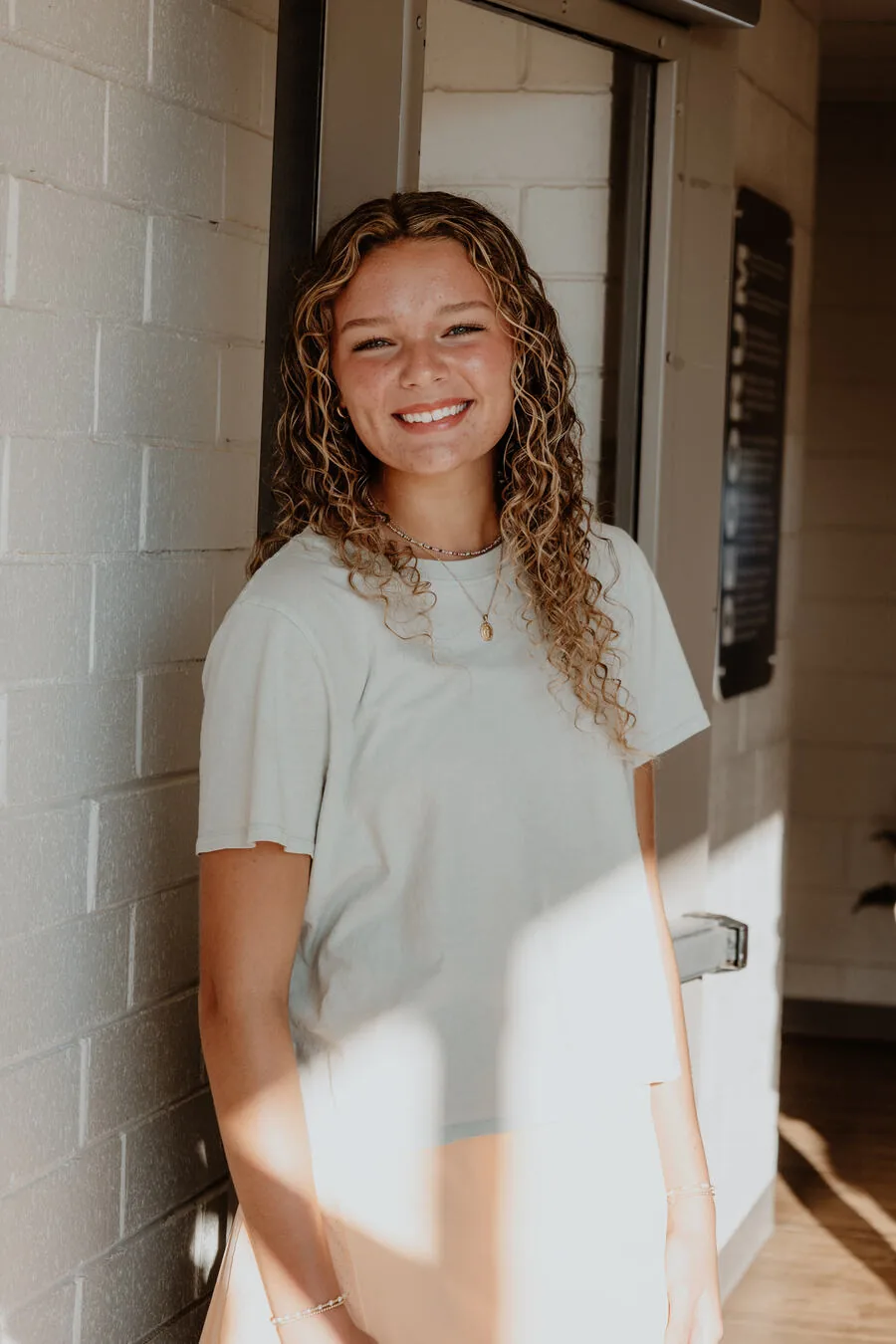 A student smiling against the wall.