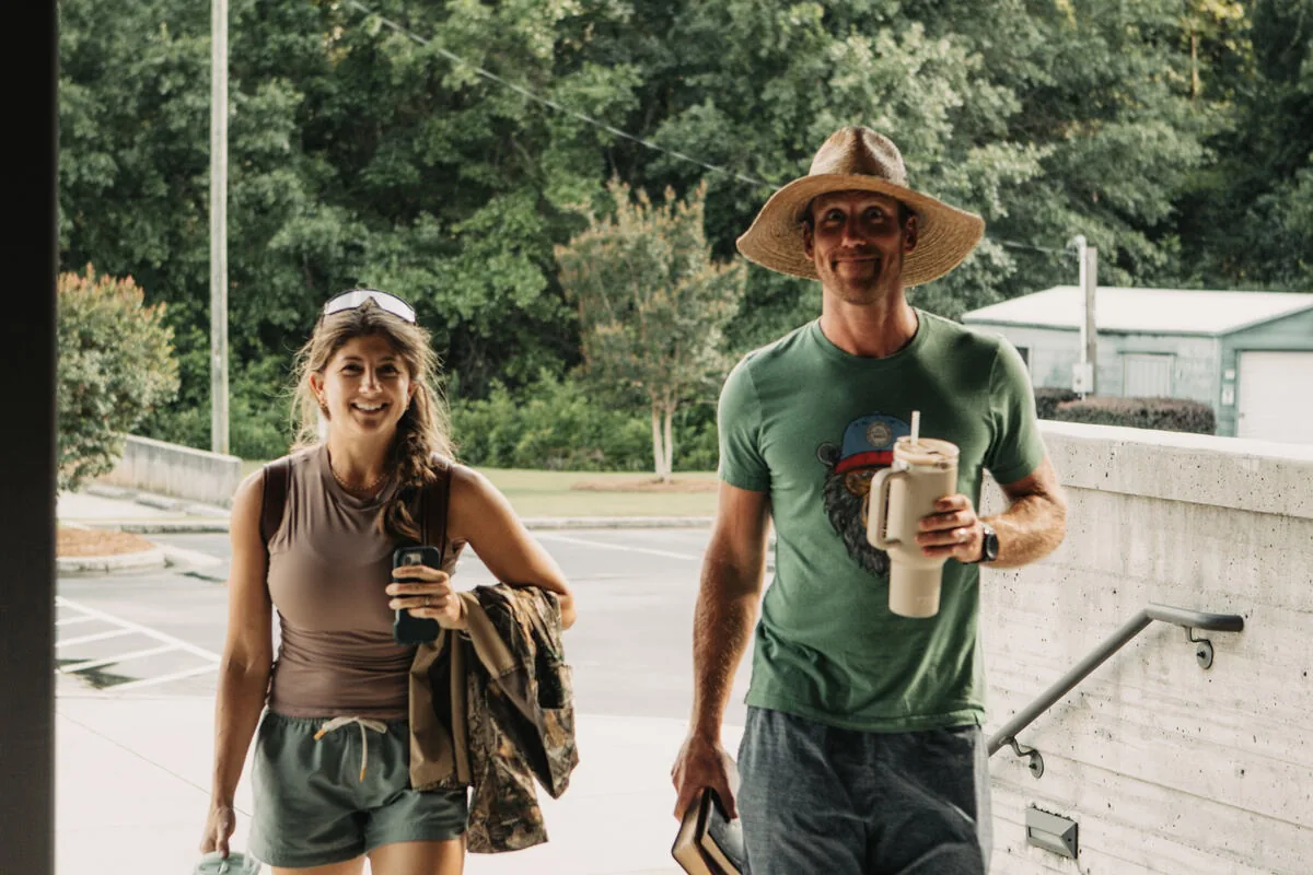 Two students walking outside with drinks.