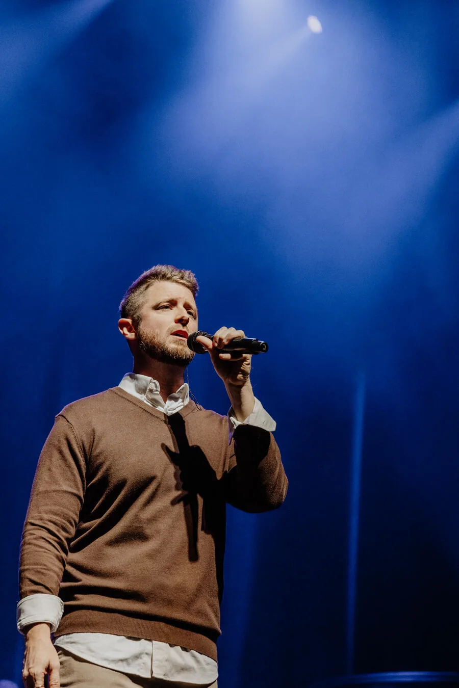 A vocalist singing under the stage lights.