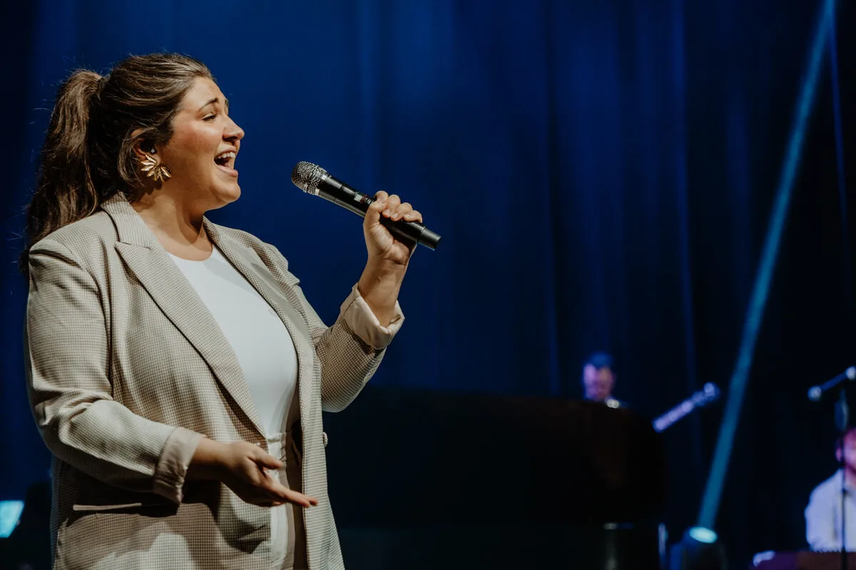 A vocalist smiling as she sings.