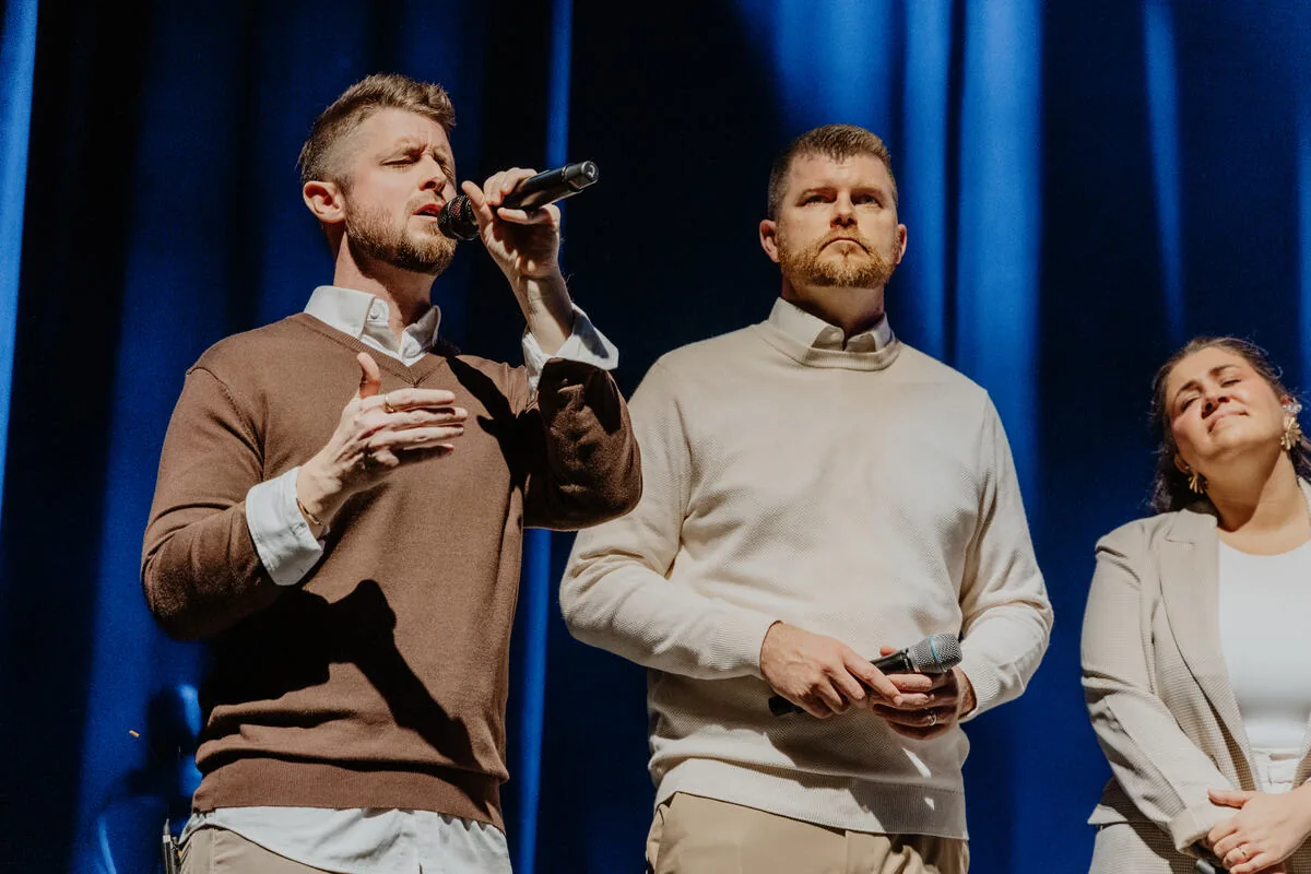 Three vocalists singing together.